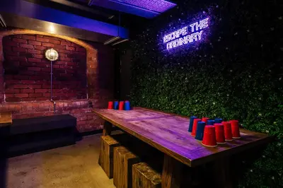 a wooden table in a room with a neon sign at Kabannas Liverpool in Liverpool