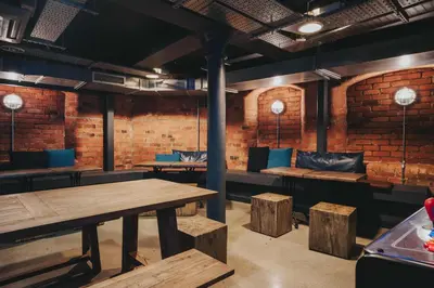 a restaurant with wooden tables and benches and a brick wall at Kabannas Liverpool in Liverpool