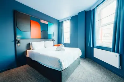 a bedroom with a bed with blue walls and windows at Kabannas Liverpool in Liverpool