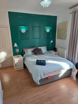 a bedroom with a large bed with a green headboard at Spacious Double Room in Anfield in Liverpool