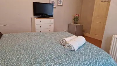 a bedroom with a bed with towels and a tv at Spacious Double Room in Anfield in Liverpool