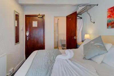 a bedroom with a white bed and a wooden door at The Strathdon in Blackpool