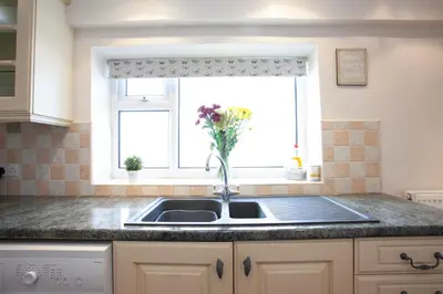 a kitchen sink with a vase of flowers in a window at Spacious 3 bedroom Cottage in Whalley in Whalley