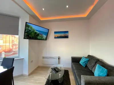 a living room with a couch and a tv on the wall at Princess Theatre Beach View Apartments by Blackpool Service Apartments in Blackpool