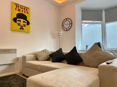 a living room with a couch and a clock on the wall at Princess Theatre Beach View Apartments by Blackpool Service Apartments in Blackpool