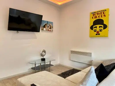 a living room with a couch and a tv on the wall at Princess Theatre Beach View Apartments by Blackpool Service Apartments in Blackpool