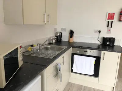 a kitchen with white cabinets and black counter tops at Princess Theatre Beach View Apartments by Blackpool Service Apartments in Blackpool