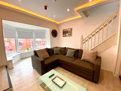 a living room with a brown couch and stairs at Princess Theatre Beach View Apartments by Blackpool Service Apartments in Blackpool