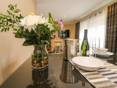 a vase of flowers on a table with a bottle of wine at Kilmory Lodge in Poulton le Fylde