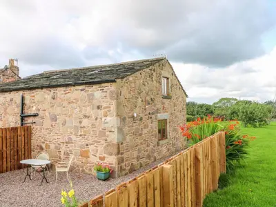 a stone barn with a table and chairs in a yard at The Croft in Chorley