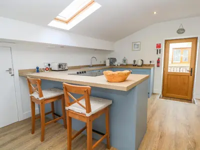 a kitchen with a sink and a counter with two chairs at The Croft in Chorley