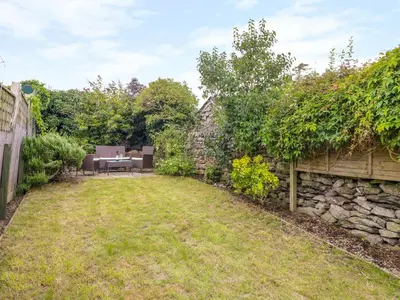 a garden with a stone wall and a table at Molly's Cottage in Grange Over Sands
