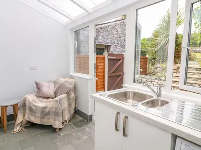 a kitchen with a sink and a chair next to a window at Molly's Cottage in Grange Over Sands