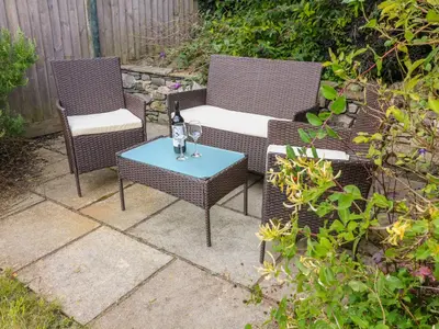 two wicker chairs and a table with a bottle of wine at Molly's Cottage in Grange Over Sands