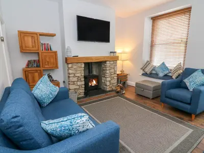 a living room with a blue couch and a fireplace at Molly's Cottage in Grange Over Sands