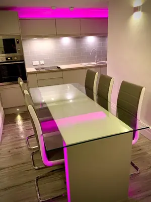 a kitchen with a table and chairs with pink lighting at Salt-Rock in Blackpool