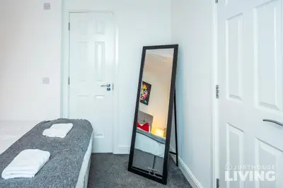 a bedroom with a mirror next to a bed at NEW Spacious Modern Townhouse Sleeps 12 Free Parking in Liverpool