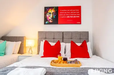 a bed with red pillows and a tray of food on it at NEW Spacious Modern Townhouse Sleeps 12 Free Parking in Liverpool