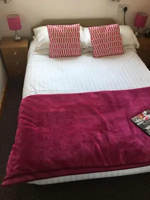 a bed with a purple blanket on top of it at Kingscliff in Blackpool