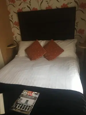 a bed with two pillows and a magazine on it at Kingscliff in Blackpool
