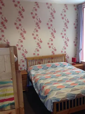 a bedroom with a bed with pink flowers on the wall at Lindisfarne Holiday Apartments - Families & Couples Only in Blackpool