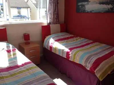 a small bedroom with two beds and a window at Lindisfarne Holiday Apartments - Families & Couples Only in Blackpool