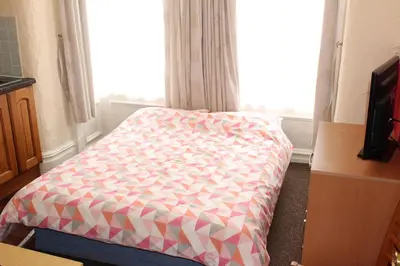 a bed sitting in a room with a window at Lindisfarne Holiday Apartments - Families & Couples Only in Blackpool