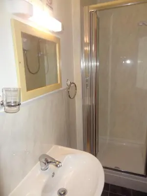 a bathroom with a sink and a shower with a mirror at Lindisfarne Holiday Apartments - Families & Couples Only in Blackpool
