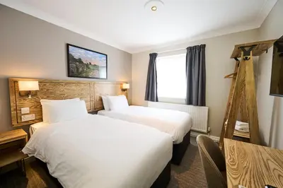 a hotel room with two beds and a window at Red Lion, Wigan by Marston's Inns in Rufford