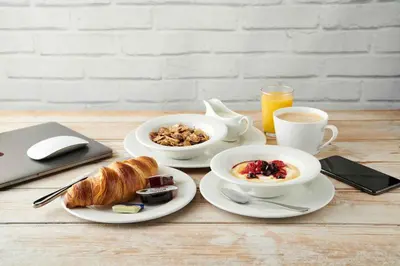 a table with two plates of breakfast food and a laptop at Red Lion, Wigan by Marston's Inns in Rufford