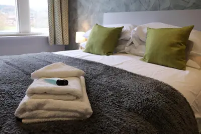 a bed with a pile of towels on it at The Bridge Inn Hotel in Bolton