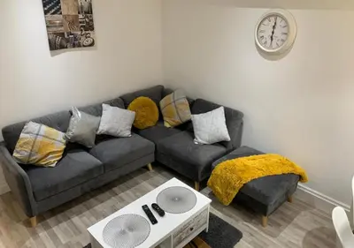 a living room with a couch and a clock on the wall at Parton Residence in Liverpool