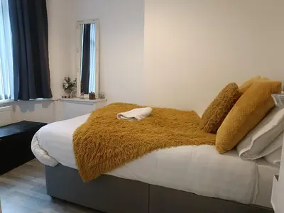 a bed with a brown blanket and pillows on it at Parton Residence in Liverpool