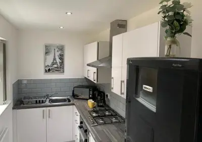 a kitchen with white cabinets and a black refrigerator at Parton Residence in Liverpool