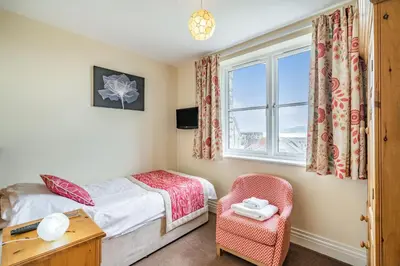 a bedroom with a bed and a chair and a window at Hillberry in Grange Over Sands