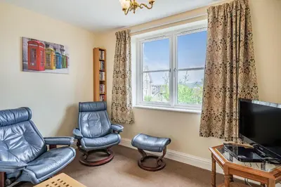 a living room with a tv and chairs and a window at Hillberry in Grange Over Sands