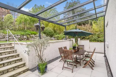 a patio with a table and chairs and an umbrella at Hillberry in Grange Over Sands