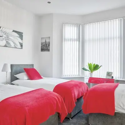 two beds with red covers in a white bedroom at Priory Suites in Liverpool
