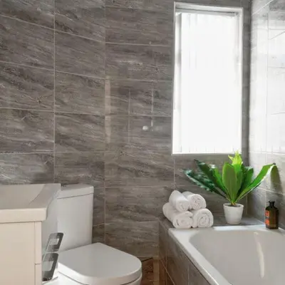 a bathroom with a toilet and a tub and a window at Priory Suites in Liverpool
