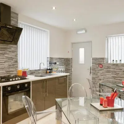 a kitchen with a glass table and chairs in it at Priory Suites in Liverpool