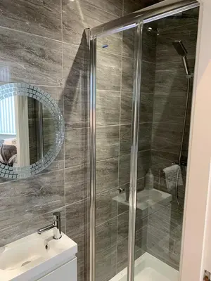 a bathroom with a shower with a sink and a mirror at Priory Suites in Liverpool