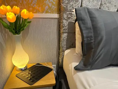 a table with a vase of orange tulips next to a bed at Raffles Hotel in Blackpool