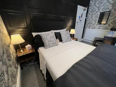 a bedroom with a large white bed and two lamps at Raffles Hotel in Blackpool