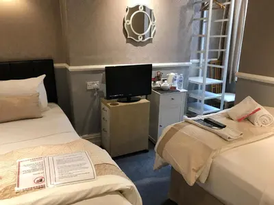 a hotel room with two beds and a television at Raffles Hotel in Blackpool
