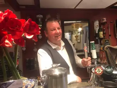 a man standing behind a bar holding a wine glass at Raffles Hotel in Blackpool
