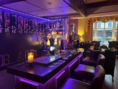 a bar in a restaurant with purple lighting at Raffles Hotel in Blackpool