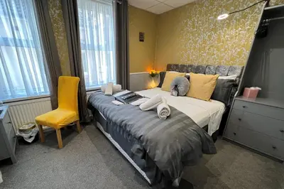 a bedroom with a bed and a yellow chair at Raffles Hotel in Blackpool