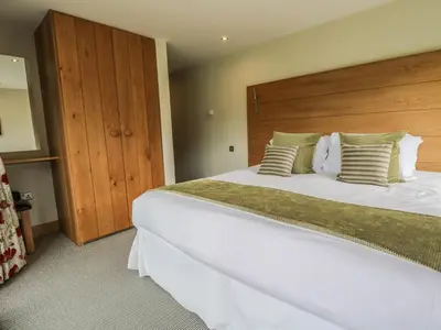 a bedroom with a large white bed with a wooden headboard at Neddy Cut in Ulverston