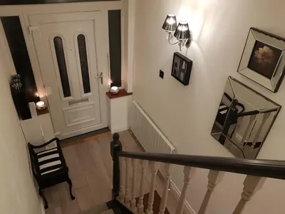 a hallway with a staircase with a door and a chair at Luxury 5* Home with Secret Garden and Free Parking in Liverpool
