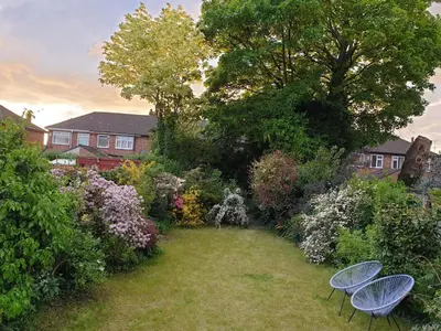 two chairs sitting in a garden with flowers at Luxury 5* Home with Secret Garden and Free Parking in Liverpool